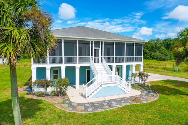 rear view of property with a sunroom, a patio area, and a yard