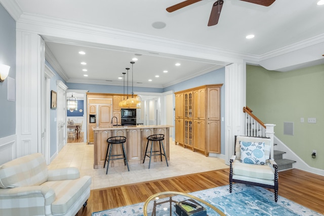 living area with crown molding, light wood finished floors, and stairs