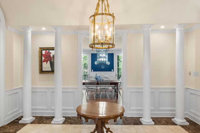 dining room featuring ornate columns, ornamental molding, and a decorative wall