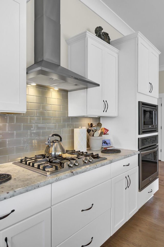 345 Turnstone St, Mount Pleasant, SC 29464 - kitchen featuring decorative backsplash, stainless steel appliances, wall chimney exhaust hood, dark wood finished floors, and white cabinetry