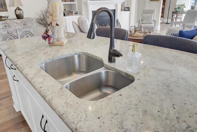 345 Turnstone St, Mount Pleasant, SC 29464 - kitchen featuring a warm lit fireplace, light stone countertops, white cabinetry, a sink, and open floor plan