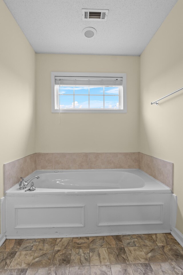 331 Kinard St, Orangeburg, SC 29118 - bathroom featuring a garden tub, a textured ceiling, and stone finish flooring