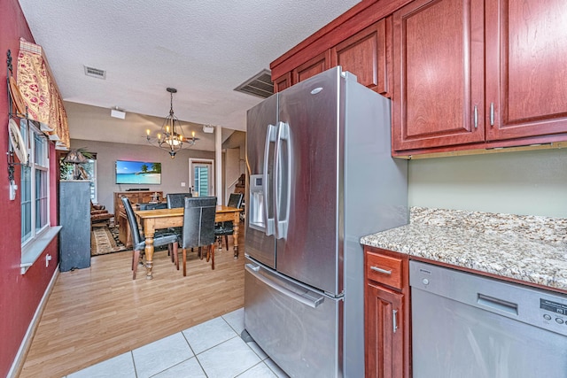 kitchen featuring stainless steel refrigerator with ice dispenser, a textured ceiling, dishwasher, and a notable chandelier