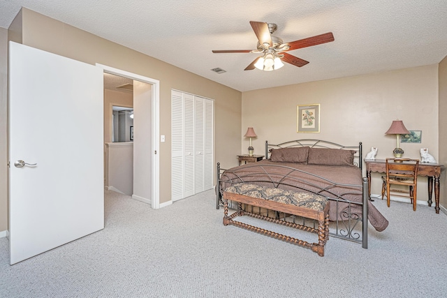 carpeted bedroom with ceiling fan, a closet, and a textured ceiling