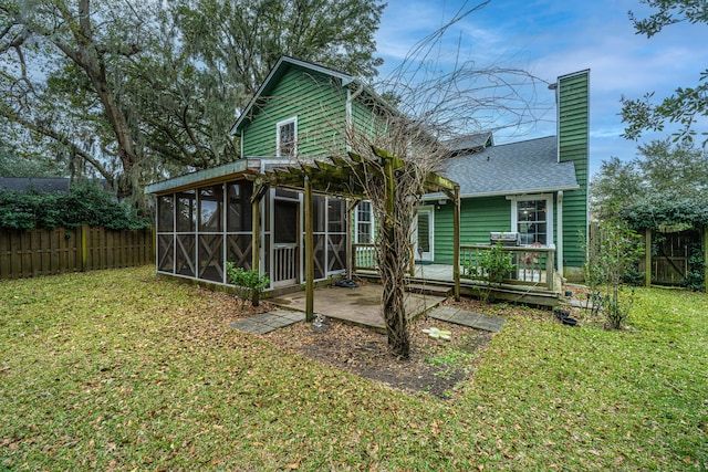 back of house with a wooden deck, a sunroom, and a lawn