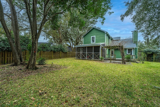 rear view of house featuring a lawn and a sunroom