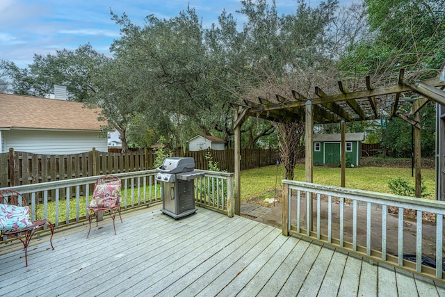 wooden terrace with a pergola, a storage unit, a yard, and grilling area