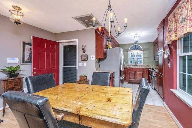 dining room featuring an inviting chandelier, light wood-type flooring, and a textured ceiling