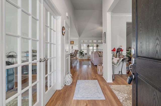 entrance foyer with ornamental molding, french doors, and light hardwood / wood-style flooring