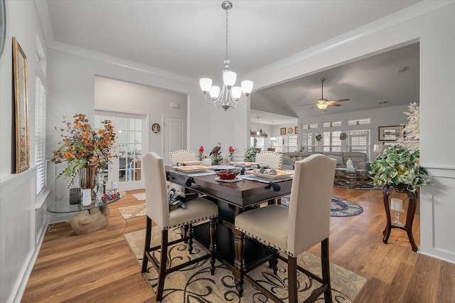 dining room with ceiling fan with notable chandelier, wood-type flooring, and ornamental molding