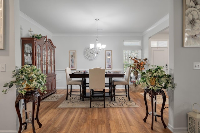 dining space with light wood-type flooring, an inviting chandelier, and crown molding