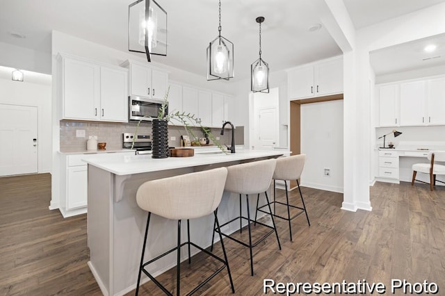 kitchen with dark wood-style floors, white cabinetry, stainless steel appliances, and a sink