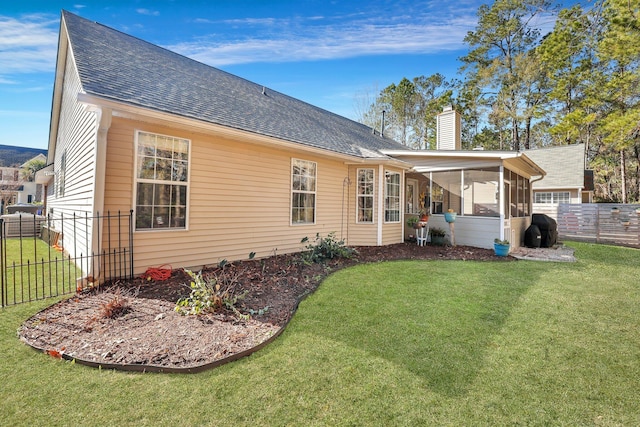 rear view of house with a yard and a sunroom