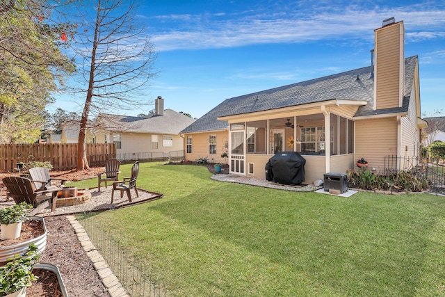 back of property with a yard, an outdoor fire pit, and a sunroom