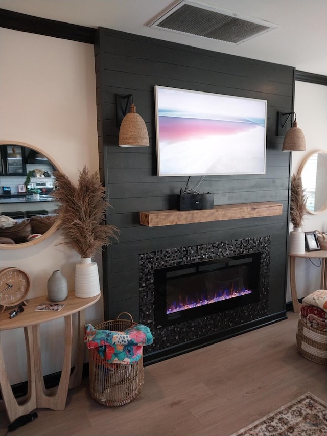 interior details featuring hardwood / wood-style floors, ornamental molding, and a tile fireplace