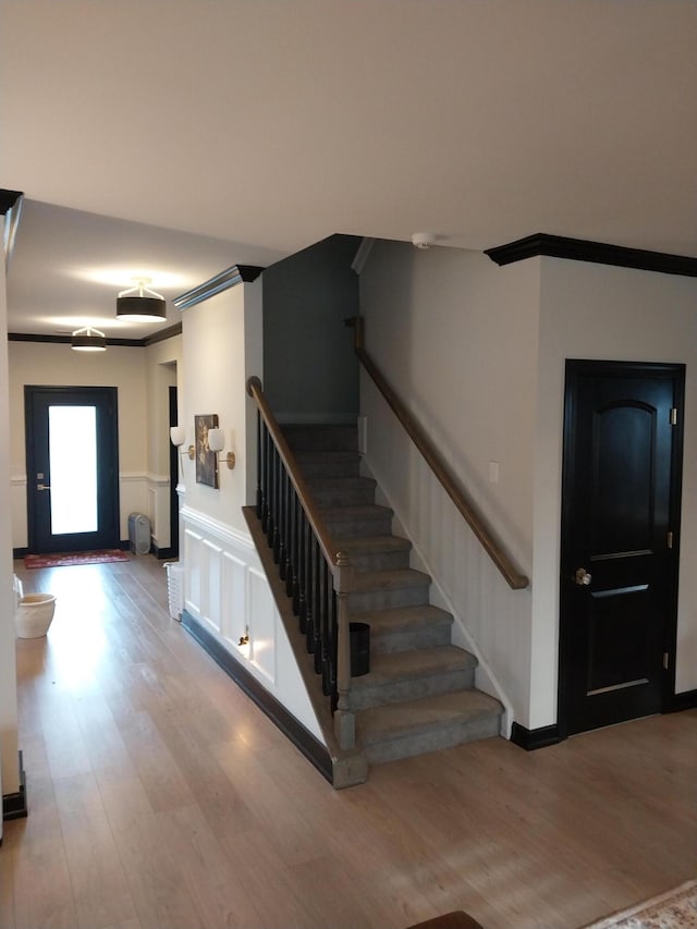 stairs with hardwood / wood-style flooring and crown molding