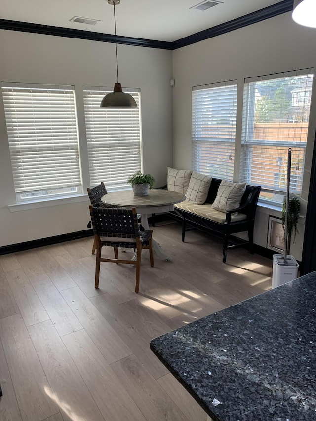 dining room with crown molding and light hardwood / wood-style flooring