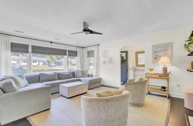 living area featuring visible vents, wood finished floors, baseboards, ceiling fan, and arched walkways