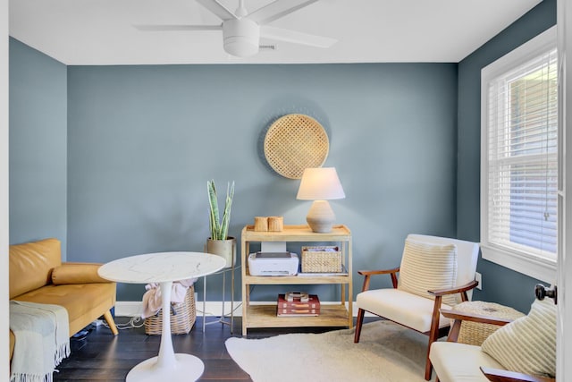 living area with baseboards, a ceiling fan, and wood finished floors