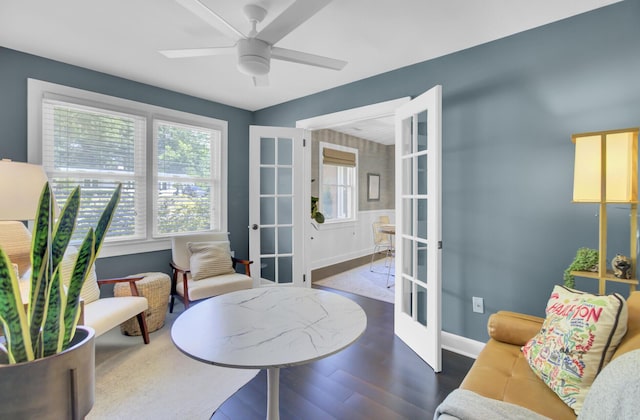 living area with french doors, a ceiling fan, baseboards, and wood finished floors