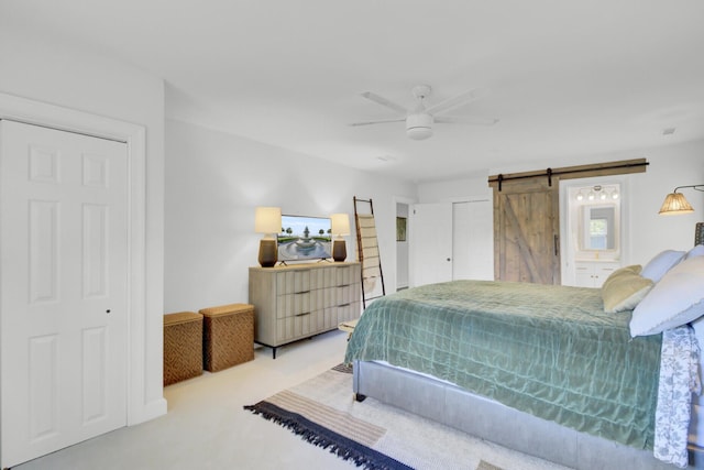 carpeted bedroom featuring ceiling fan and a barn door