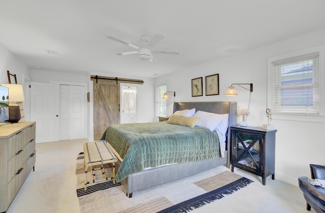 bedroom with a ceiling fan, a barn door, multiple windows, and light carpet