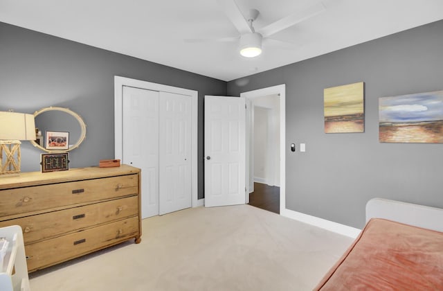 bedroom with baseboards, ceiling fan, light carpet, and a closet