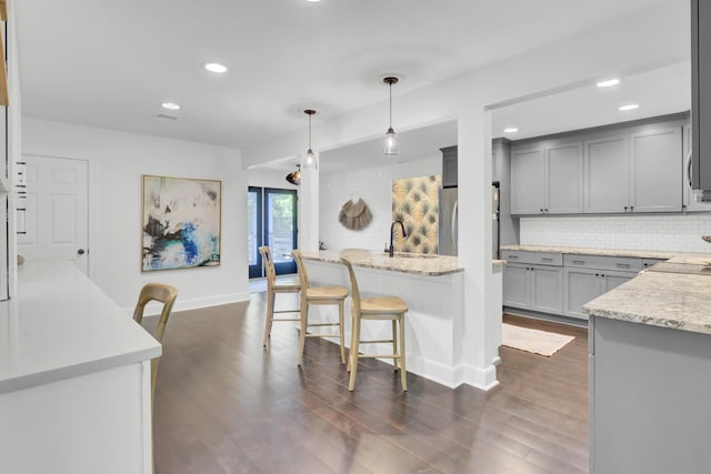 kitchen with gray cabinetry, baseboards, tasteful backsplash, and dark wood-type flooring
