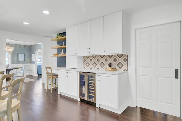 bar with beverage cooler, recessed lighting, decorative backsplash, dark wood-type flooring, and a bar