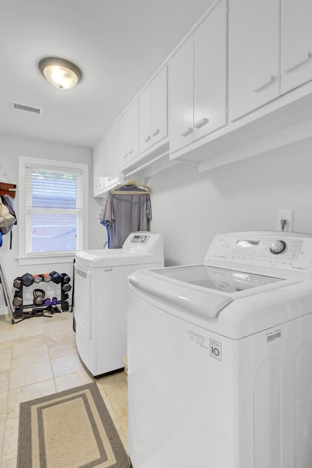 clothes washing area featuring cabinet space, separate washer and dryer, visible vents, and light tile patterned floors
