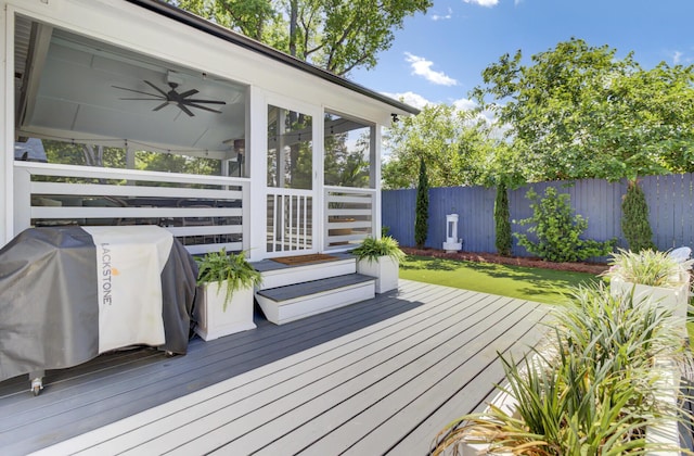 wooden deck with ceiling fan, a fenced backyard, and a sunroom