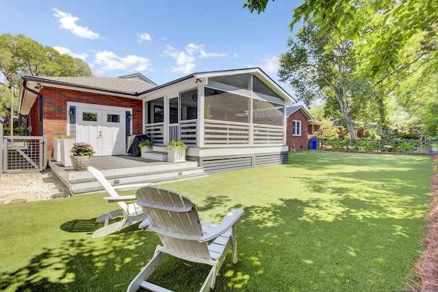 back of property with a lawn, a deck, a sunroom, brick siding, and a shingled roof