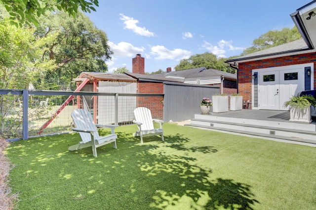 view of yard with a deck, a fenced backyard, and a playground