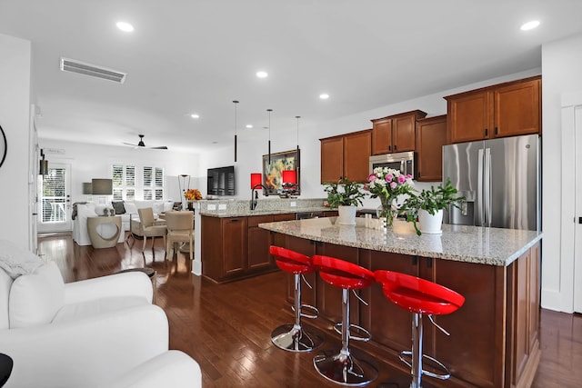 kitchen featuring a center island, hanging light fixtures, ceiling fan, a breakfast bar area, and stainless steel appliances