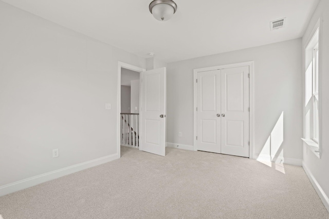 unfurnished bedroom featuring a closet and light colored carpet