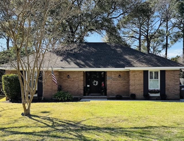 single story home featuring a front yard, brick siding, and roof with shingles