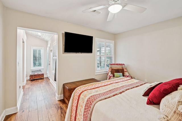 bedroom with lofted ceiling, visible vents, a ceiling fan, wood finished floors, and baseboards