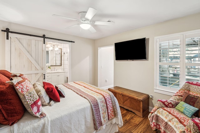 bedroom with a barn door, multiple windows, baseboards, and wood finished floors