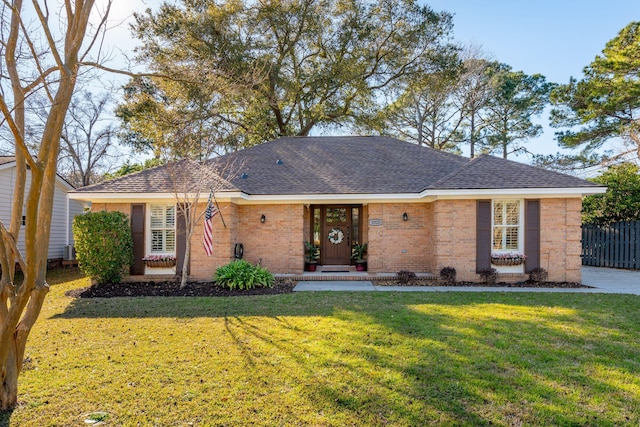 ranch-style home featuring roof with shingles, fence, a front lawn, and brick siding