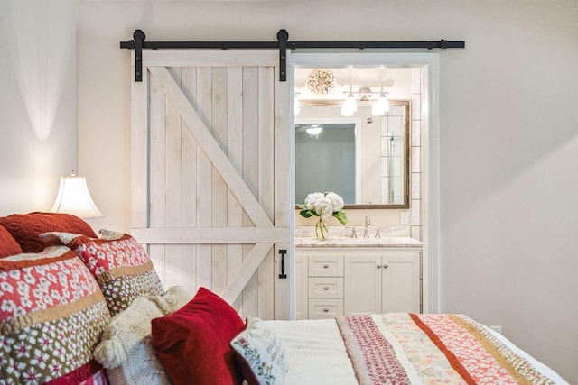 bedroom featuring connected bathroom, a sink, and a barn door