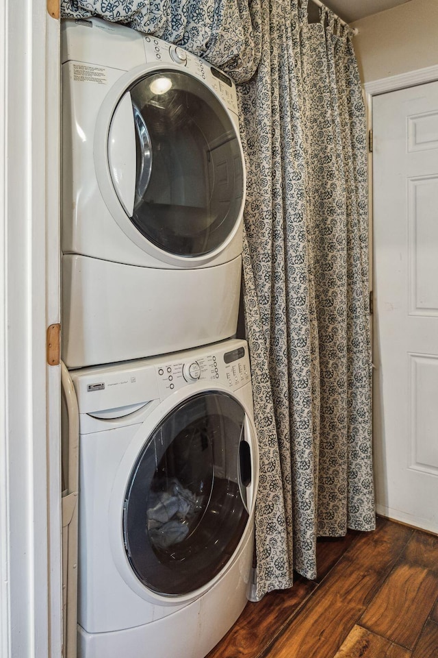 laundry area featuring stacked washer and dryer, wood finished floors, and laundry area