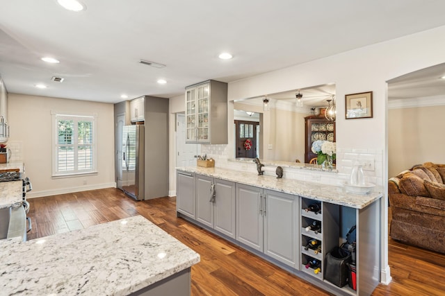 kitchen with stainless steel appliances, decorative backsplash, dark wood finished floors, and gray cabinetry