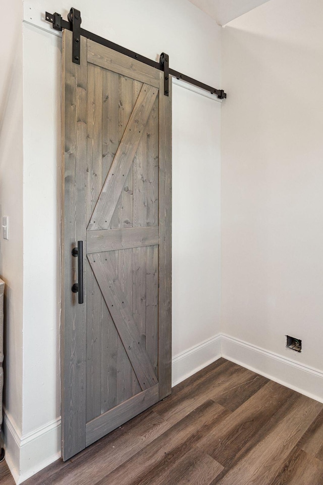 room details with wood finished floors, baseboards, and a barn door