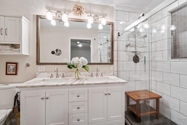 full bathroom with toilet, double vanity, a sink, and tiled shower