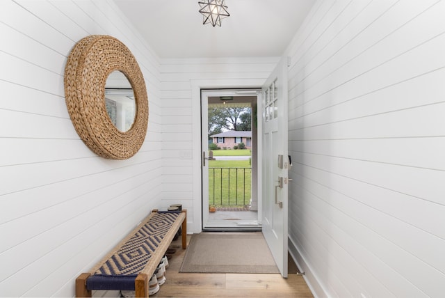 doorway to outside with hardwood / wood-style flooring and wooden walls