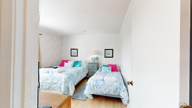 bedroom featuring ornamental molding, hardwood / wood-style flooring, and a textured ceiling