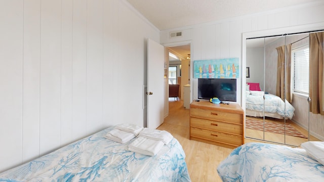 bedroom with ornamental molding, a closet, and light wood-type flooring