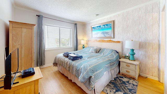 bedroom featuring ornamental molding, light hardwood / wood-style flooring, and a textured ceiling