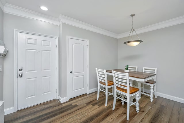 dining room featuring crown molding, dark wood-type flooring, and baseboards