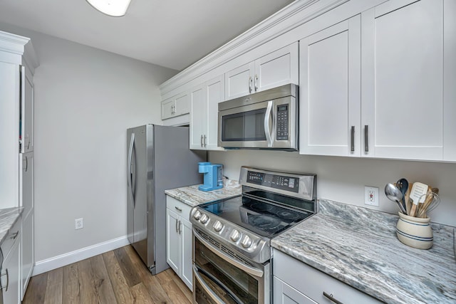 kitchen with stainless steel appliances, light stone countertops, dark wood-style flooring, and white cabinetry